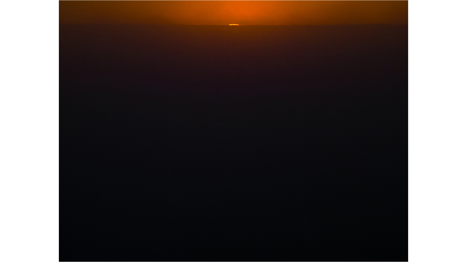 sunset, just a sliver of sun above clouds